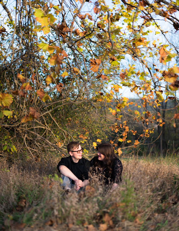 A couple is framed by fall leaves during their fall engagement session