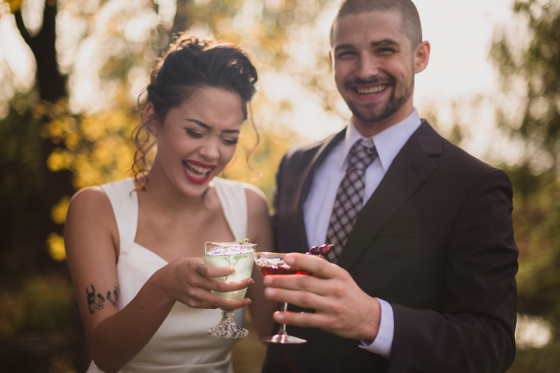 A husband and wife clink their glasses together during their wedding at Ballenger Farm
